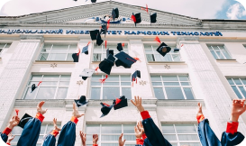 Un groupe de diplômés lance sa casquette en l'air devant un bâtiment universitaire. Notre mission est d'améliorer la réussite des étudiants et d'éliminer les abandons scolaires évitables, sans alourdir la charge des administrateurs.