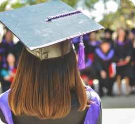 A graduate stands with her back to the camera, clad in her cap and gown. Our mission is to improve student success and eliminate preventable student dropouts — without putting more burden on administrators.