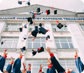 A group of graduates throw their black graduate caps in the air