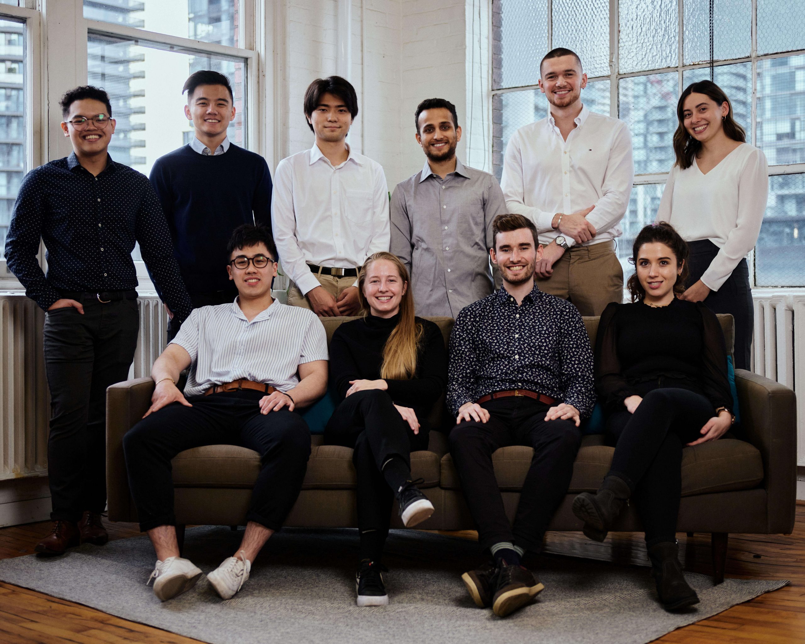 The Nimbus Learning – a group of 10 professionally dressed workers smile for the camera. They are all posed standing or sitting on a blue couch
